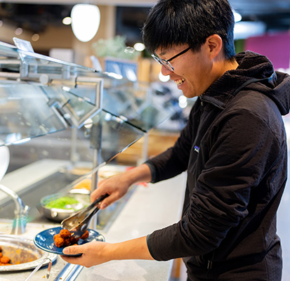 A student serving themselves a plate at San Juan Dining Hall